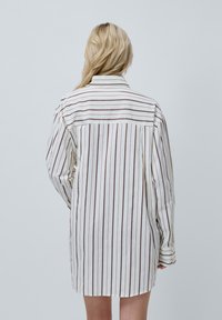 Gestreepte jurk in wit en bruin, met een kraag, lange mouwen en een ontspannen silhoette met een gebogen zoom.