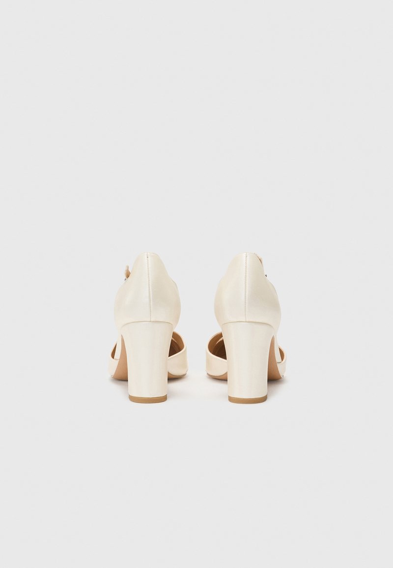 Scarpe con tacco beige in pelle liscia, con punta arrotondata e tacco grosso. Design con apertura sul retro e dettagli con cinturino.