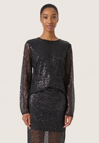 Abito nero a paillettes con maniche lunghe, scollo rotondo e silhouette aderente. Texture scintillante, design a strati che accentua il movimento.