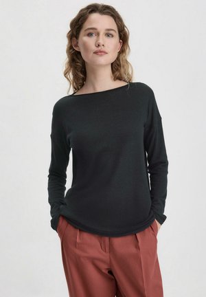 Zwarte lange mouwen top met een brede bootnek, een gladde textuur en een relaxte pasvorm. In combinatie met roestkleurige, geplooide broeken.