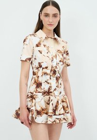 Blommönstrad kort klänning i beige och bruna toner, med krage, knappstängning fram och utsvängd nederkant samt midja med bälte.