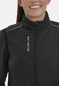 Schwarze leichte Sportjacke mit Reißverschluss, hohem Kragen, reflektierenden Akzenten und "ELITE LAB"-Logo auf der Vorderseite.