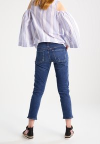 Ljusblå denimjeans med smal passform, med bakfickor och en lätt slitning, kombinerat med en randig off-the-shoulder topp.