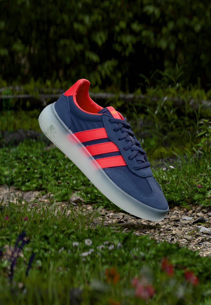 Granatowe sneakersy z różowymi akcentami, z trzema paskami po boku, okrągłym noskiem i przezroczystą podeszwą. Gładka tekstura z sznurowanym zapięciem.