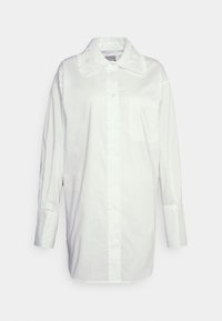 Camisa branca de botão em algodão, com colarinho rendado, mangas longas, um único bolso no peito e um design reto.