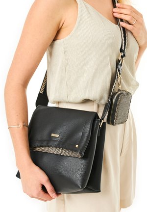 Sac en cuir noir texturé en bandoulière avec une poche zippée accentuée de doré et une petite pochette amovible, doté d'une sangle ajustable et durable.