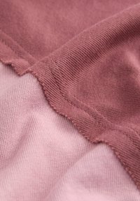 Stofmonsters in zacht roze en stoffig rozenkleur met een fijne brei-textuur. Zichtbare naden en randen tonen een lichte rafeling.