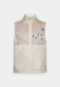 Ελαφρύ μπεζ αμάνικο γιλέκο από γυαλιστερό ύφασμα ripstop. Διαθέτει ψηλό γιακά, φερμουάρ μπροστά και διακριτικά μαύρα γραφικά.