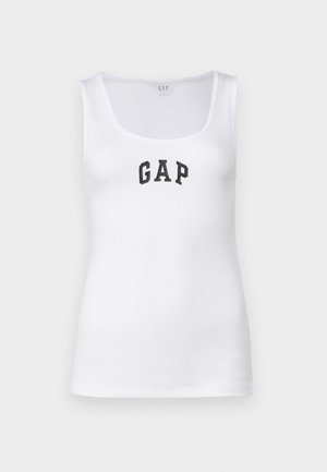 Valge tops, millel on ümar kaelus ja laiad rihmad. Rinnal on must "GAP" logo. Ribikujuline tekstuur.