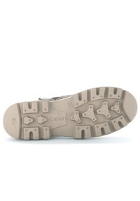 Suela de zapato color beige claro con goma texturizada para tracción, que presenta varios patrones de tacos y la marca "Gabor" en relieve.
