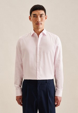 Camicia a righe rosa chiaro con colletto a punta, maniche lunghe e bottoni bianchi, abbinata a pantaloni blu scuro. Tessuto dalla consistenza liscia.