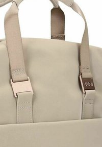 Zaino beige chiaro realizzato in materiale sintetico liscio, con spallacci in tessuto regolabili e una fibbia metallica con dettaglio logo sulla parte anteriore.