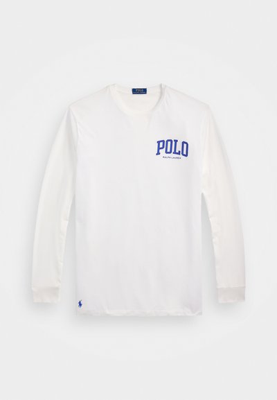 Balta ilgomis rankovėmis marškinėliai, pagaminti iš medvilnės, su mėlynu "POLO" logotipu ant kairio krūtinės ir mažu mėlynu polo žaidėjo emblemu šalia apačios.