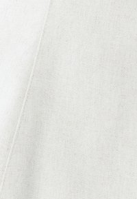 Lichtbeige textiel met een subtiel geweven patroon; heeft een schone, schuine naad en een egale, matte afwerking.