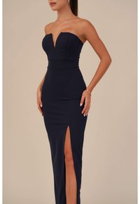 Navy strapless mekko, jossa on syvä V-pääntie, istuva vartalo ja reiden korkeuteen ulottuva halkio. Sileä, joustava kangas tarjoaa virtaviivaisen siluetin.