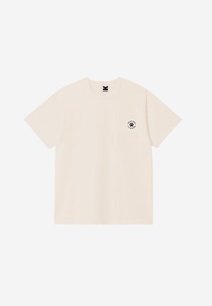 Μπεζ κοντομάνικο μπλουζάκι με λαιμόκοψη, με μικρό μαύρο κυκλικό λογότυπο που απεικονίζει πατημασιά στη αριστερή πλευρά του στήθους.