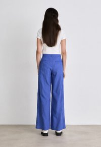 Blue striped wide-leg trousers with a high waist, made from smooth fabric. Features two back pockets and a structured fit.