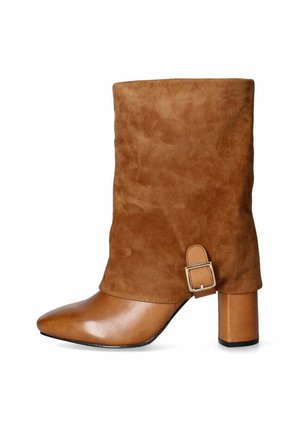 Stivaletti alla caviglia in suede marrone con punta appuntita, tacco a blocco e una cinturina con dettaglio della fibbia argentata nella parte superiore. Texture morbida in tutto il design.