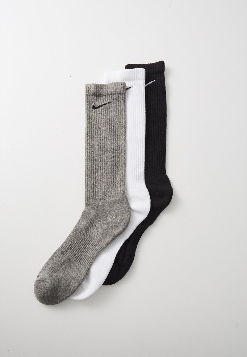 Trois paires de chaussettes de créw en gris, blanc et noir. Chacune a une texture côtelée et un petit logo Nike noir près du haut.