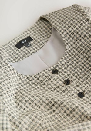 Ruuduline kleit kreemjas ja mustas värvitoonis, millel on ümar krae, kolm musta nuppu ja sile sisemine vooder mugavuse tagamiseks. Brändi silt on nähtav.