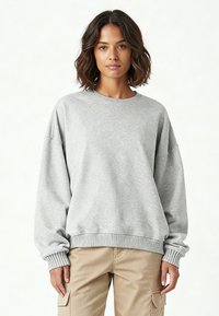 Felpa grigia con collo rotondo, spalle scese e polsini e orlo a coste. Realizzata in tessuto morbido con una vestibilità ampia, senza motivi né dettagli.