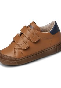 Sneaker in pelle tan con doppie straps in velcro, design arrotondato, suola in gomma testurizzata e tacco con accentuazione blu navy. Fodera interna morbida.