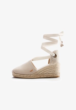 Beige Leinenschuh-Espadrille mit gewobenem Jute-Wedge, ausgestattet mit einem überkreuzten Knöchelriemen und einem strukturierten Absatzakzent. Dezentes Logo-Detail sichtbar.