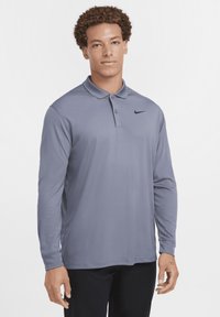 Long-sleeve, gray Nike polo shirt with a collared design and black logo on the chest. Made of smooth, lightweight material.