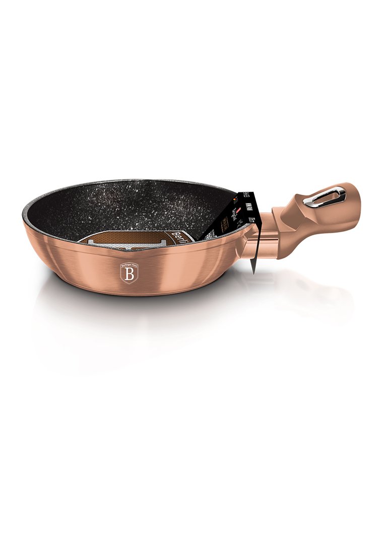 Miedziana patelnia z teksturowanym czarnym wnętrzem non-stick, ergonomiczną rączką i logo z boku, o eleganckim i nowoczesnym designie.