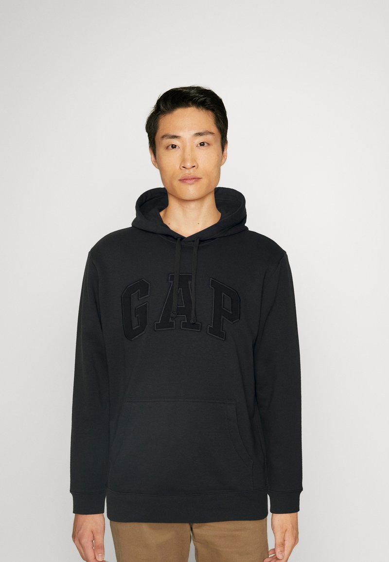 Black hoodie made of cotton blend, featuring a large embroidered "GAP" logo on the front, drawstring hood, and front pocket.