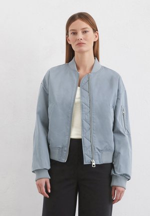 Hellblaue Bomberjacke mit Reißverschluss vorne, gerippten Bündchen und seitlichen Taschen. Verfügt über gestepptes Design an den Seiten für zusätzliche Textur.