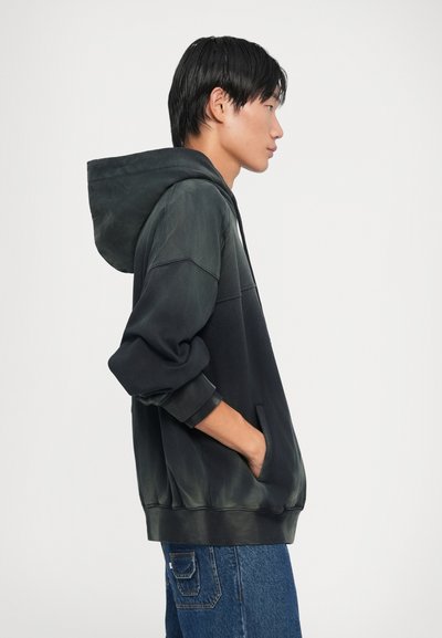 Fekete és zöld gradient színű kapucnis pulóver. Kanguru zsebbe és bordázott mandzsettákba van építve. Laza fazonú, puha anyagból készült.