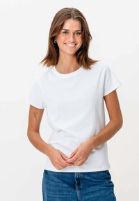 Hvid bomulds t-shirt med rund halsudskæring og korte ærmer, parret med denim. Har en glat struktur og afslappet pasform.