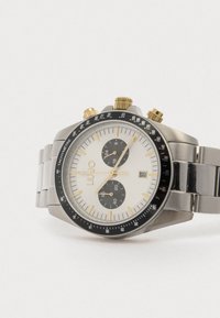 Chronograph-Uhr mit einem silbernen Edelstahlarmband, weißem Zifferblatt, schwarzen Ziffernblättern, goldenen Akzenten, schwarzem Tachymeter-Lünette und Datumsfunktion.