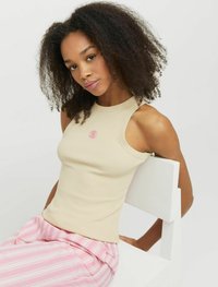 Beige ribbet tanktop med rund halsudskæring, prydet med et pink blomstermotiv. Sammenstillet med pink og hvide stribede bukser.