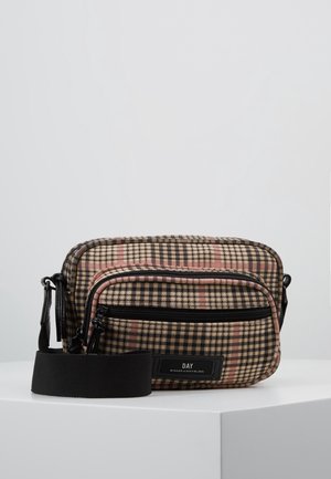 Borsa a tracolla a quadri marrone con dettagli rosa e cerniere nere, esposta su un piedistallo bianco su uno sfondo uniforme.