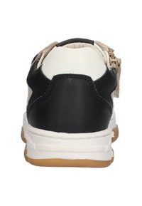 Baskets noires et blanches avec un dessus texturé, un col rembourré et un détail de fermeture éclair visible sur le côté. Semelle en gomme en bas.