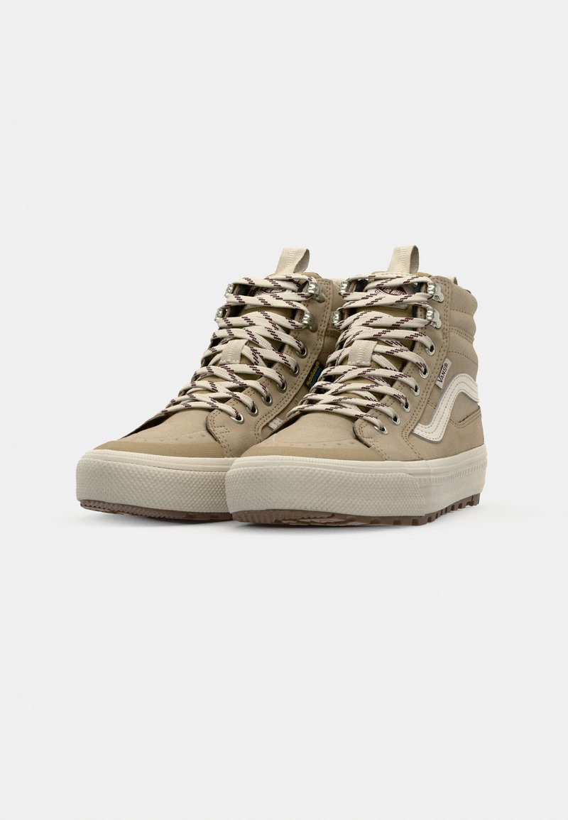Zapatillas altas beige con parte superior texturizada, cordones estampados, ojales reforzados y una franja blanca en el costado. Suela de goma con tracción.