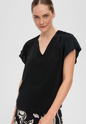 Zwarte blouse met korte mouwen en V-hals, met geplooide details op de schouders. Glad materiaal, ontspannen pasvorm, gedragen met een patroon onderstuk.