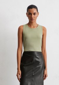 Olive green sleeveless top made from lightweight fabric, paired with a black leather skirt. Simple design with a round neckline.