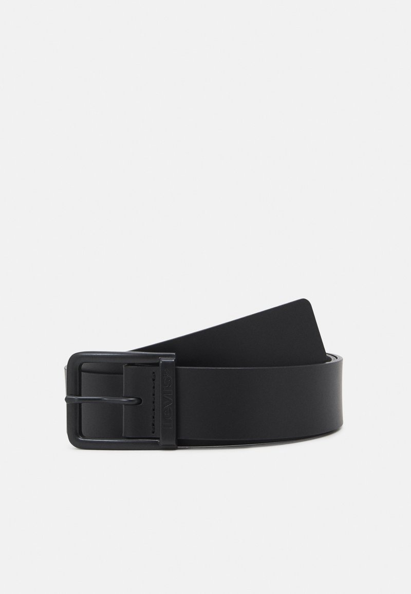 Ceinture en cuir noir roulée avec une boucle métallique rectangulaire noire mate sur un fond clair uni.