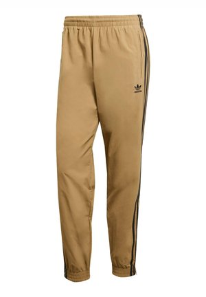 Pantalons coupe-vent beiges avec une coupe décontractée, présentant des bandes latérales noires et une taille élastique. Le matériau a une texture lisse et légère.
