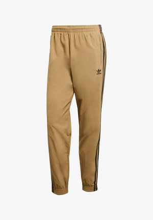 Tan windbreaker broek met een ontspannen pasvorm, voorzien van zwarte zijkanten en een elastische tailleband. Het materiaal heeft een gladde, lichtgewicht textuur.