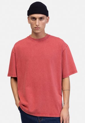 Oversized short-sleeve t-shirt in faded coral cotton. Features a crew neckline, relaxed fit, and subtle stitching details.