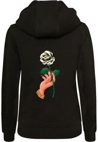 Felpa nera con un grafico colorato che raffigura una mano che tiene una rosa bianca stilizzata con foglie verdi e un accento di catena dorata.