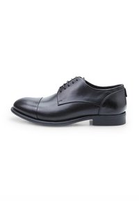 Scarpa stringata in pelle nera con punta arrotondata e dettagli di cucitura, texture liscia e tacco basso impilato. Caratterizzata da occhielli standard e un design minimal.