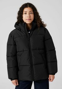 Plumífero negro con cierre de cremallera y capucha. Cuenta con secciones acolchadas y puños elasticados, combinado con una camiseta de rayas debajo.