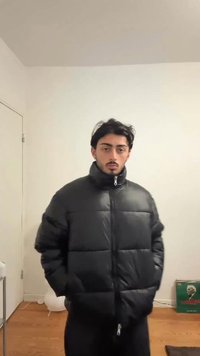 Giacca a vento nera con collo alto, chiusura con zip e design trapuntato. Il modello è posizionato su uno sfondo neutro.