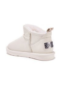 Botín de cuero blanco hasta el tobillo con superficie texturizada y forro de pelo sintético. Presenta una placa de logo metálica en el lateral y una punta blanda y redonda.