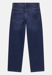 Vaqueros rectos de color azul oscuro con dos bolsillos traseros, pasadores para cinturón y un pequeño logotipo triangular negro en el bolsillo derecho.